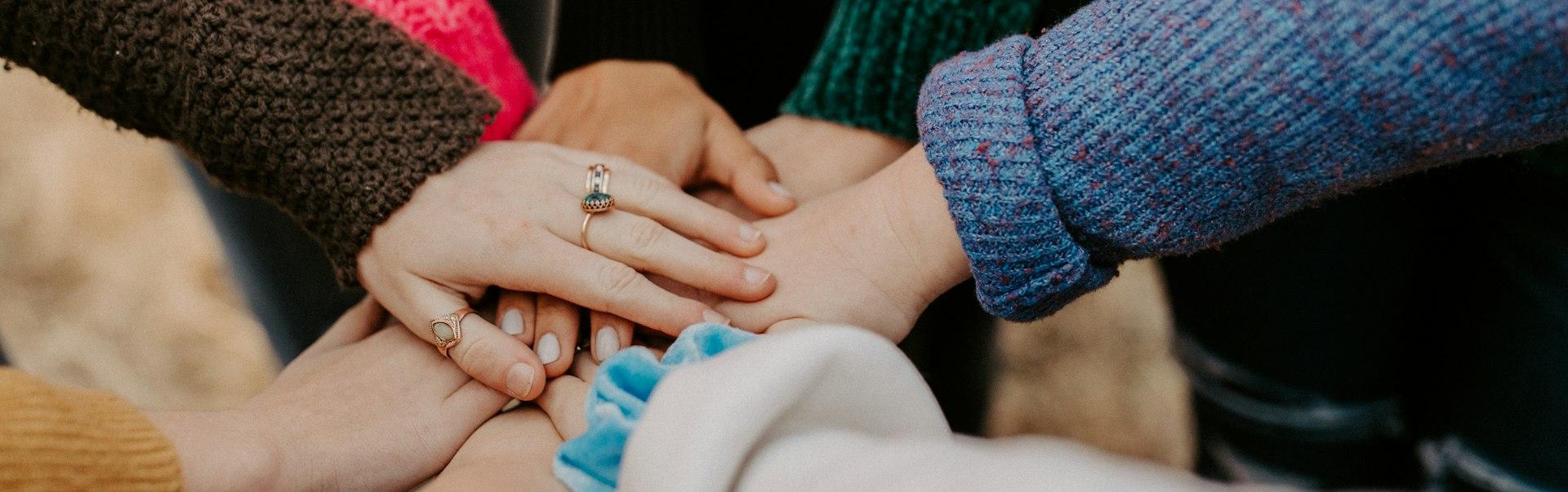 person in red sweater holding babys hand